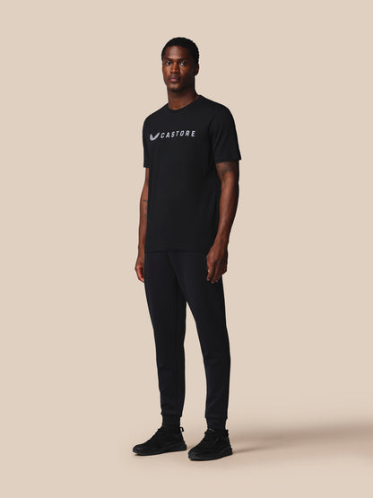 Man wearing a black t-shirt with a logo on a beige background