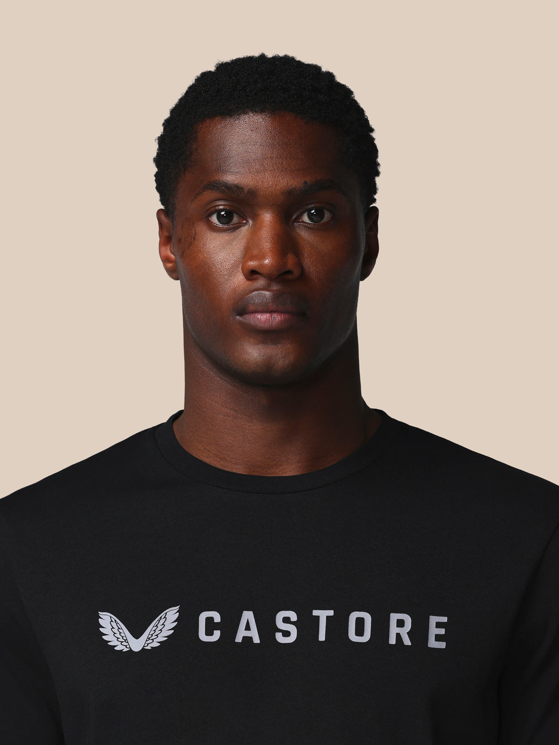 Man wearing a black Castore shirt against a beige background
