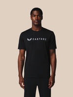 Man wearing a black t-shirt with 'Castore' logo on a beige background