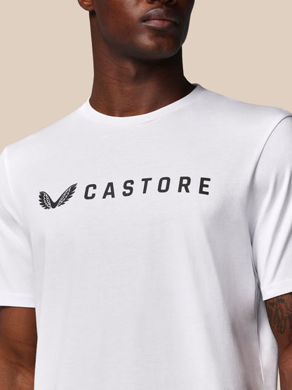 Person wearing a white t-shirt with 'CASTORE' logo on a beige background