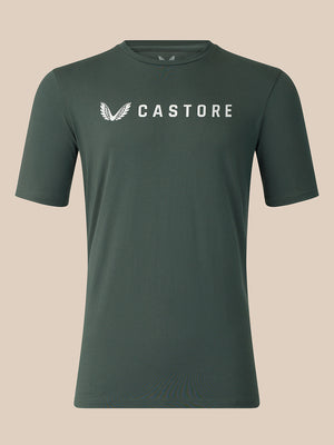 A dark green crewneck t-shirt with a white Castore logo printed on the chest, displayed against a solid beige background.