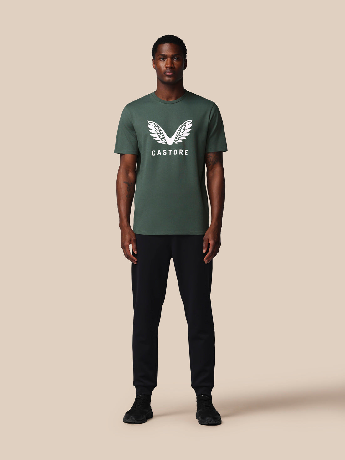 Man wearing a green t-shirt with a logo on a beige background