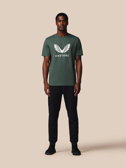 Man wearing a green t-shirt with a logo on a beige background