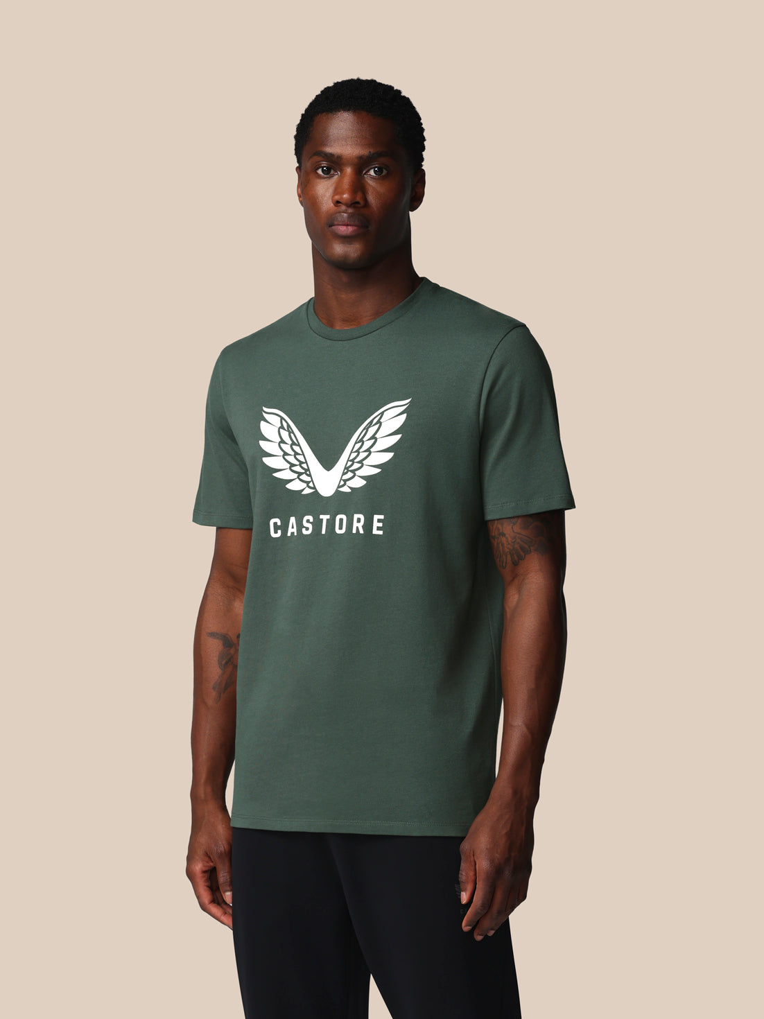 Man wearing a green t-shirt with a white logo and text on a beige background