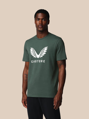Man wearing a green t-shirt with a white logo and text on a beige background