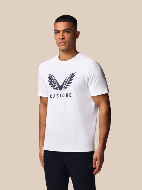 Man wearing a white t-shirt with a logo and text on a beige background