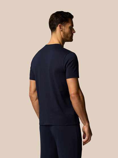 Man wearing a navy blue t-shirt and pants on a beige background