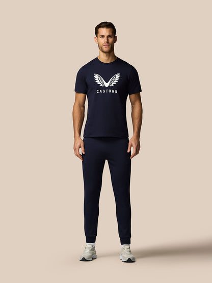 Man wearing navy blue Castore t-shirt and pants on a beige background