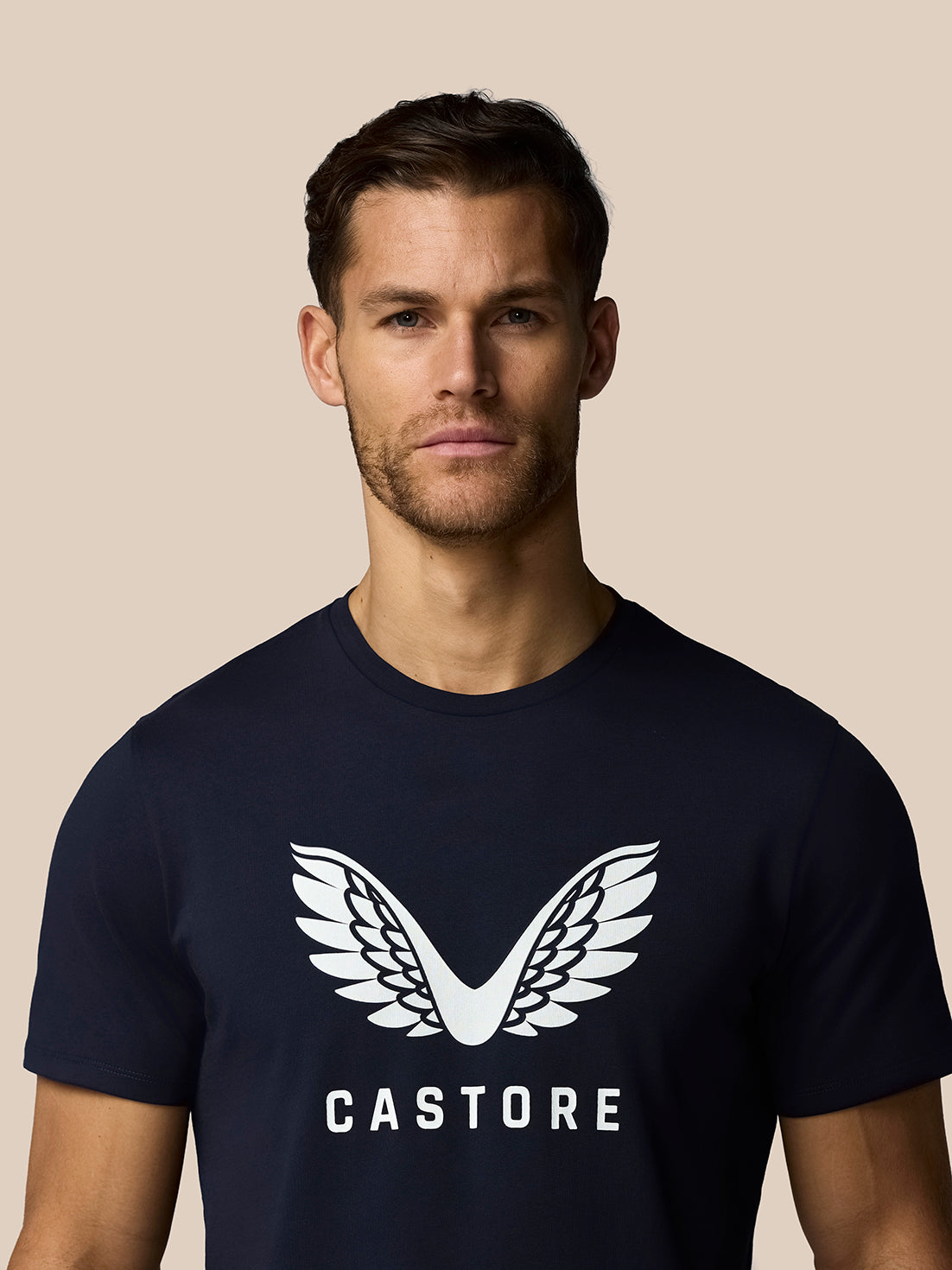 Man wearing a navy blue t-shirt with a white logo and text on a beige background