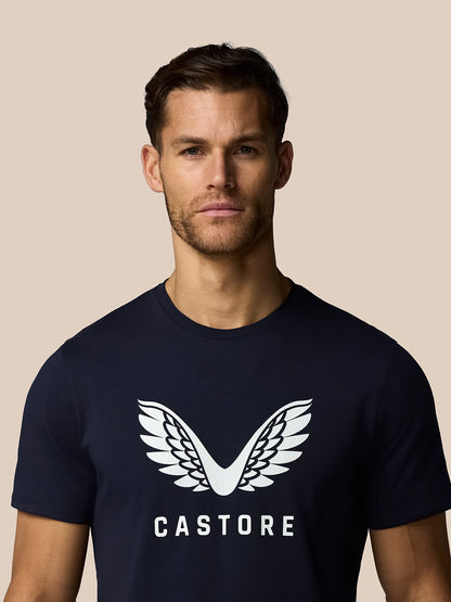 Man wearing a navy blue t-shirt with a white logo and text on a beige background