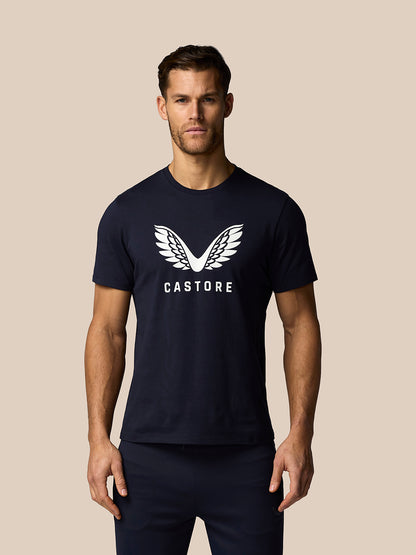 Man wearing a navy blue t-shirt with a logo and text on a beige background