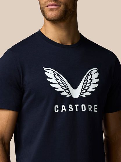 Person wearing a navy blue t-shirt with a white 'Castore' logo on a beige background