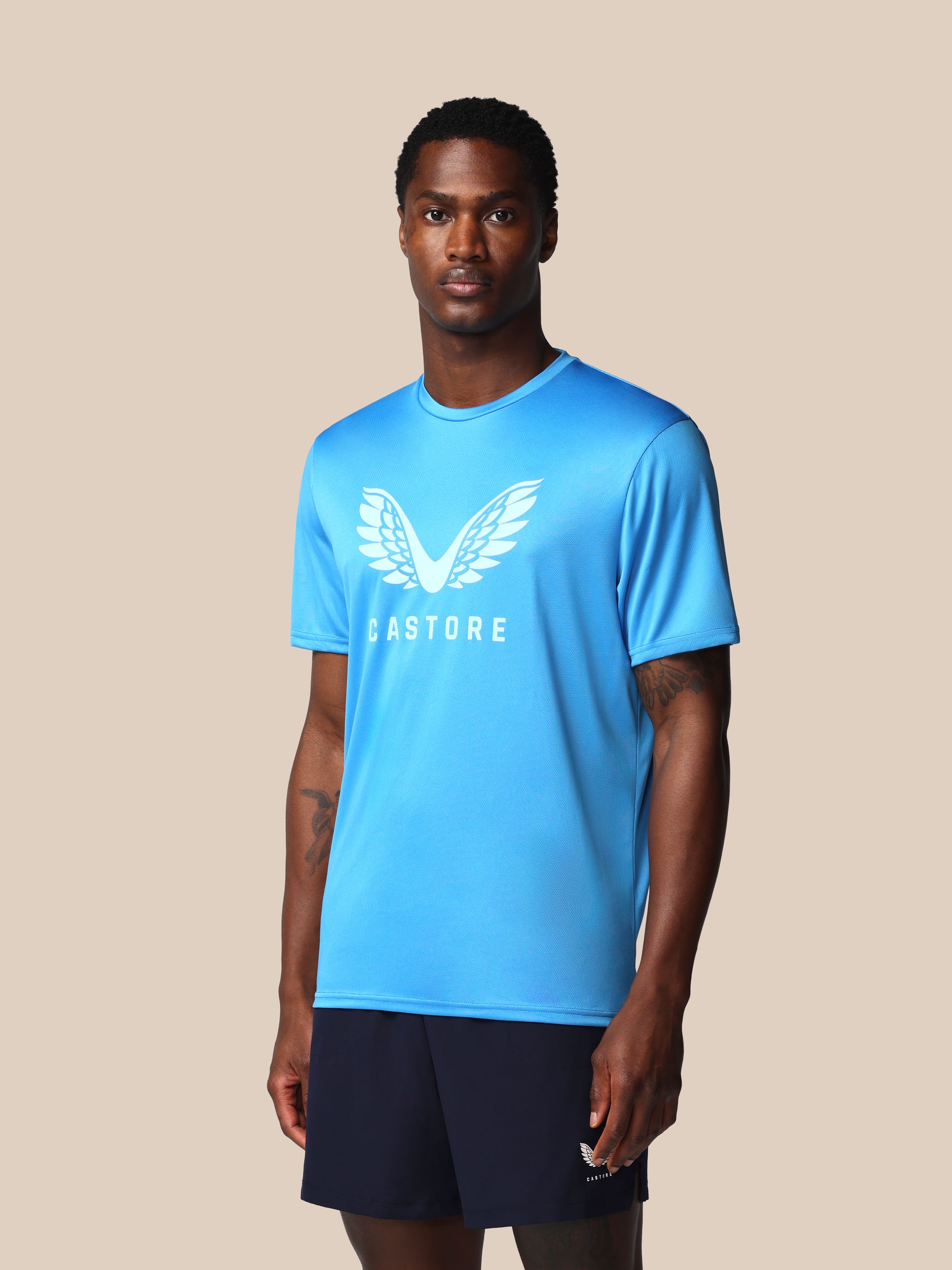 Man wearing a blue athletic shirt with a logo on a beige background