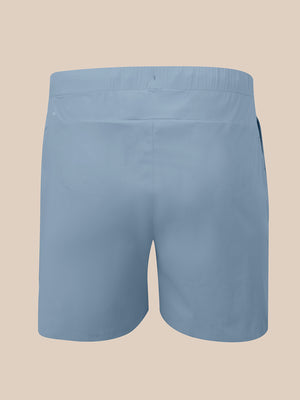 Light blue men's shorts shown from the back, featuring an elastic waistband and side pockets, set against a solid beige background.
