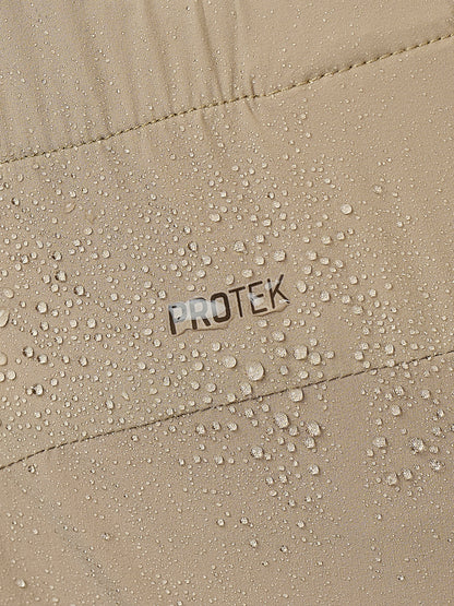 Close-up of a beige waterproof jacket or fabric with water droplets beading on the surface and the word PROTEK printed in the center.
