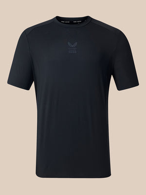 A black short-sleeve athletic t-shirt with a subtle tonal logo on the center chest, displayed against a solid beige background.