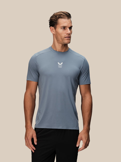 Male model wearing blue Castore Reiss performance short sleeve T shirt with small white logo at the center of the chest.