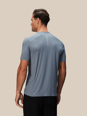Back view of a man wearing blue Reiss x Castore performance short sleeve T-shirt with a vertical logo on the upper back.