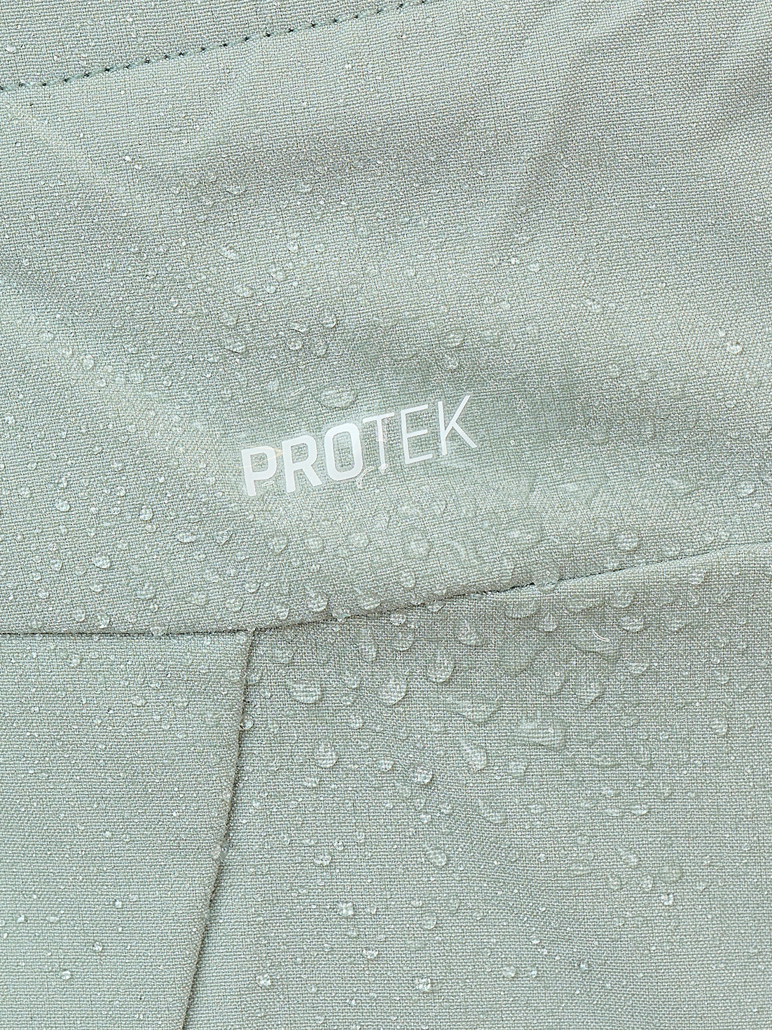 Close-up of sage mist fabric displaying ProTek branding and water droplets