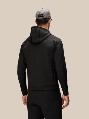 Back view of a man in black Reiss x Castore Flex Hoodie with the hood down and a grey cap