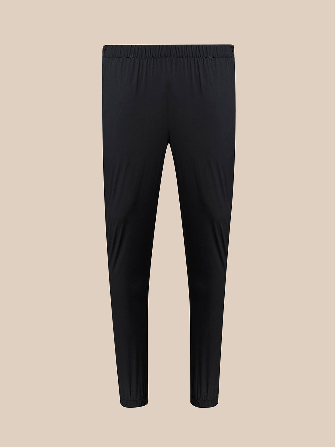 Black athletic leggings with an elastic waistband, shown flat against a solid beige background.