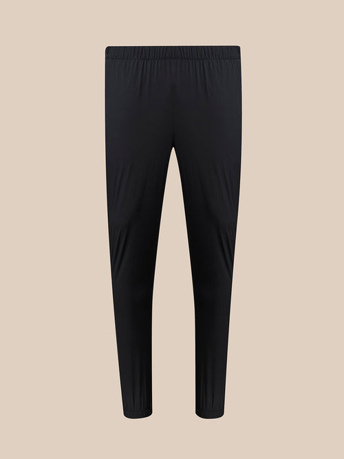 Black athletic leggings with an elastic waistband, shown flat against a solid beige background.
