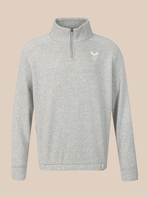 A light gray heathered quarter-zip sweatshirt with a small white winged logo on the left chest, displayed on a solid beige background.