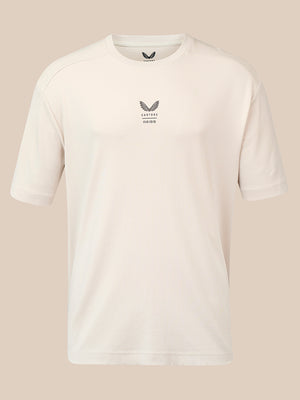 A short-sleeve crewneck athletic t-shirt in off-white, featuring a small dark gray winged logo and the text 'CASTORE' and 'REISS' printed on the centre chest, displayed against a solid beige background.