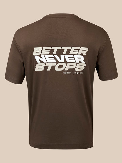 A brown short-sleeve t-shirt shown from the back, featuring a bold white graphic print that reads 'BETTER NEVER STOPS' with 'REISS | CASTORE' printed underneath, set against a solid beige background.