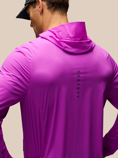 A man wearing a bright magenta-purple Castore hooded athletic jacket, shown from the back against a solid beige background.