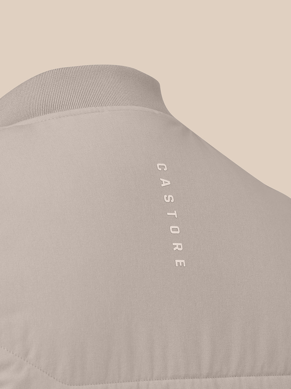 Close up of taupe back on the sleeveless gilet showing quilted upper panel and vertical CASTORE logo along the back yoke