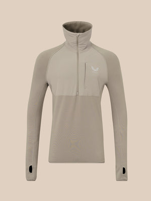 A long-sleeve quarter-zip pullover top in a light taupe-beige color, featuring a high mock neck collar, a vertical zippered chest pocket, and a small white wing logo on the left chest, displayed on a solid beige background.