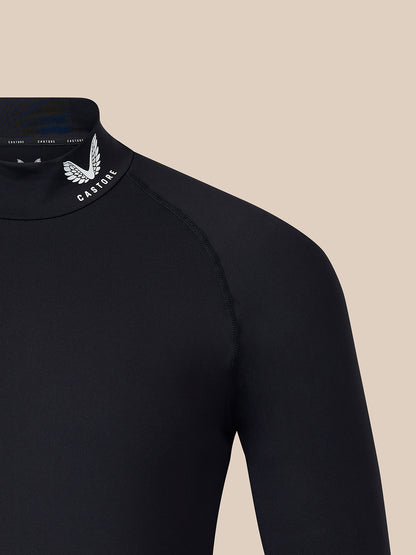 Close-up of a black long-sleeve high-neck top with a white winged logo and the word 'CASTORE' on the inner neck collar, shown against a plain beige background.