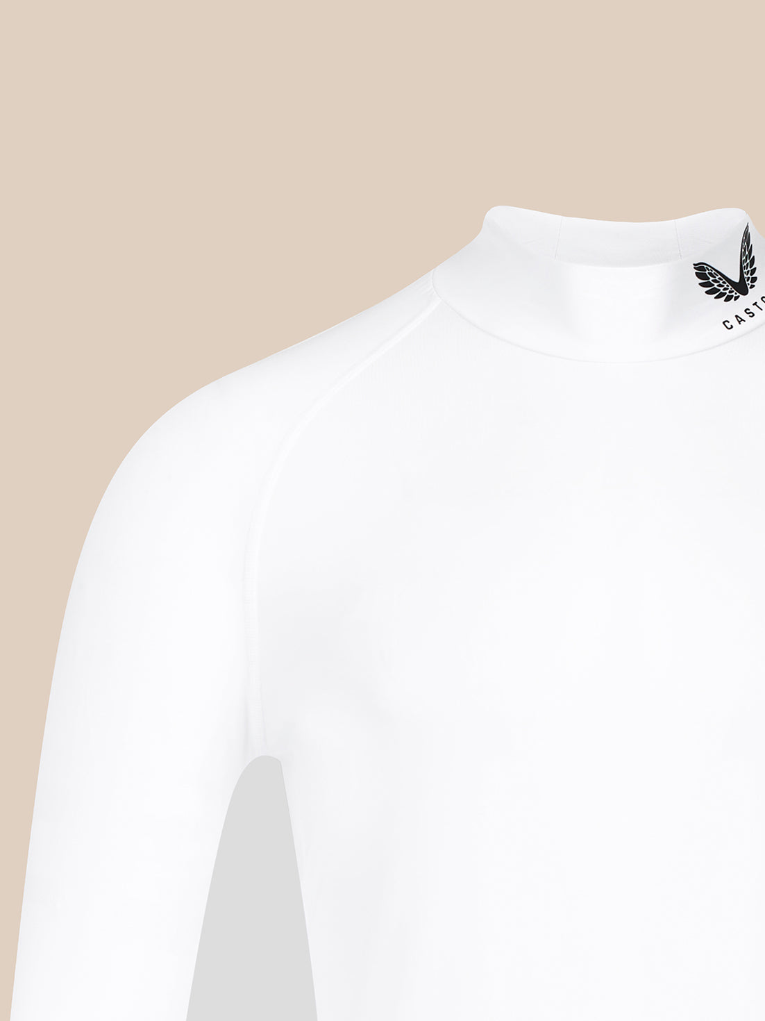 Close-up of a white long-sleeve mock neck top on a model, showing a black winged logo and the partial text 'CASTORE' on the inside of the collar, set against a solid beige background.