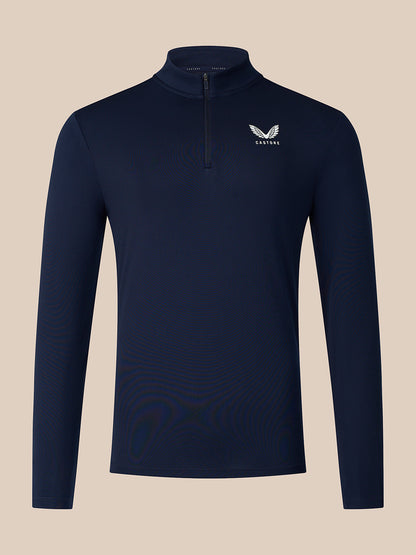 A navy blue long-sleeve quarter-zip pullover with a small white winged logo and the word 'CASTORE' on the left chest, displayed against a solid beige background.