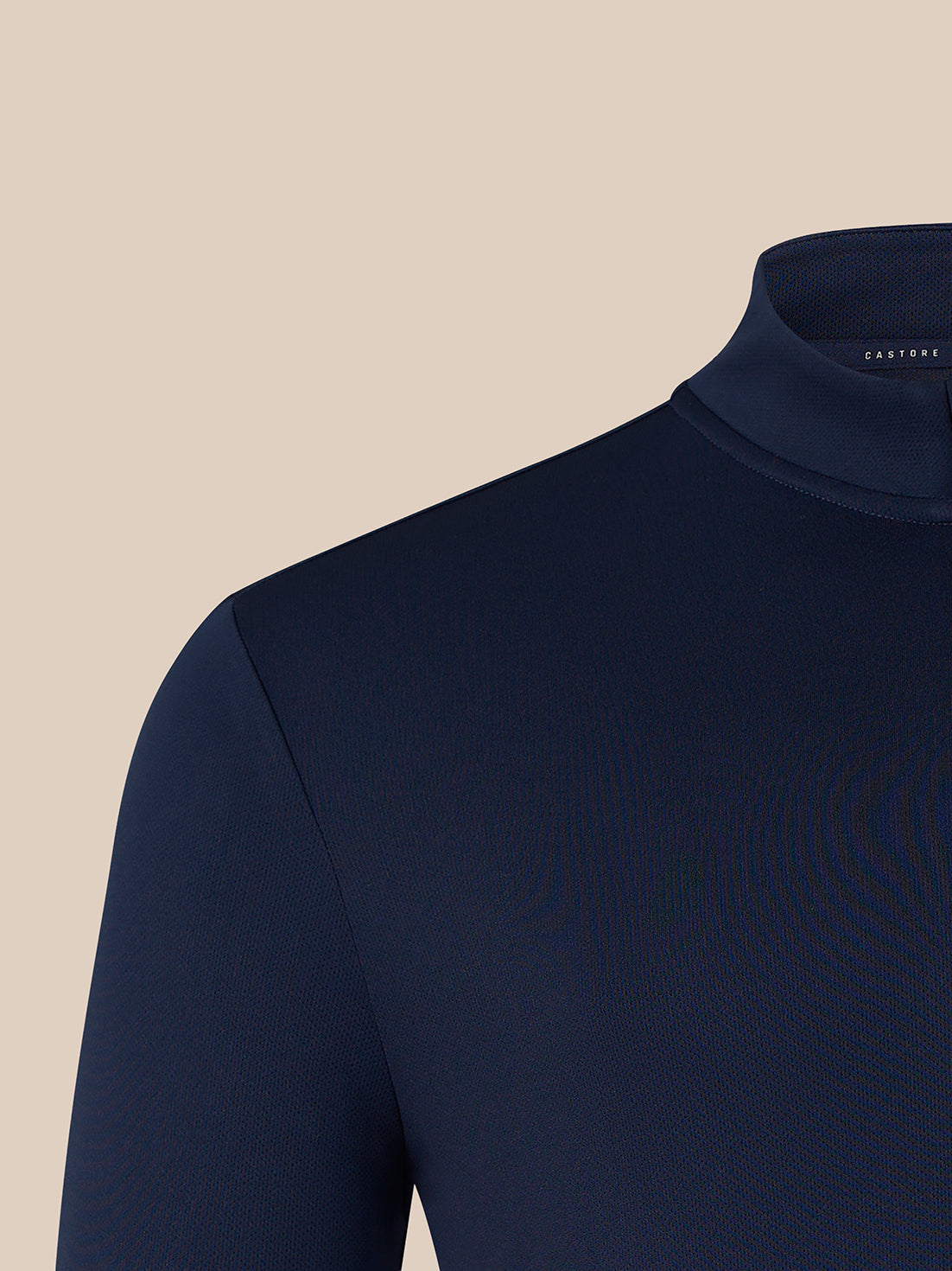 Close-up of a dark navy mock neck knit top on a mannequin, showing the collar and shoulder against a solid beige background.