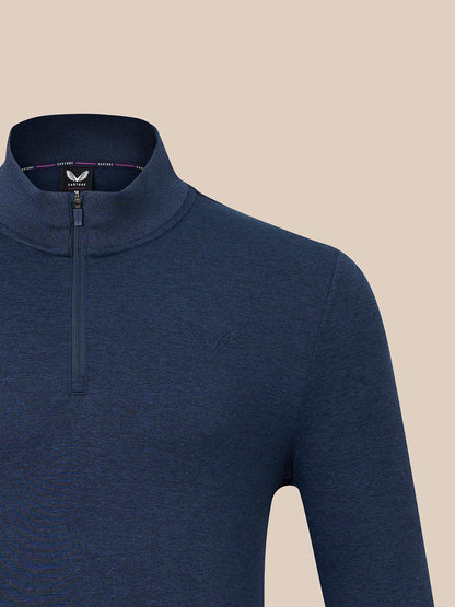 A close-up of a men's navy blue quarter-zip mock neck sweater from Castore, featuring a subtle tonal embroidered logo on the chest, set against a solid beige background.