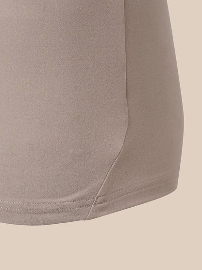 Close-up detail of a taupe-beige garment showing the side seam and hem stitching against a solid light beige background.