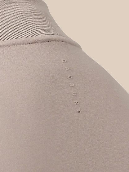 Close-up of a ribbed knit top in a light taupe-beige color, featuring the brand name 'CASTORE' vertically embroidered on the chest.