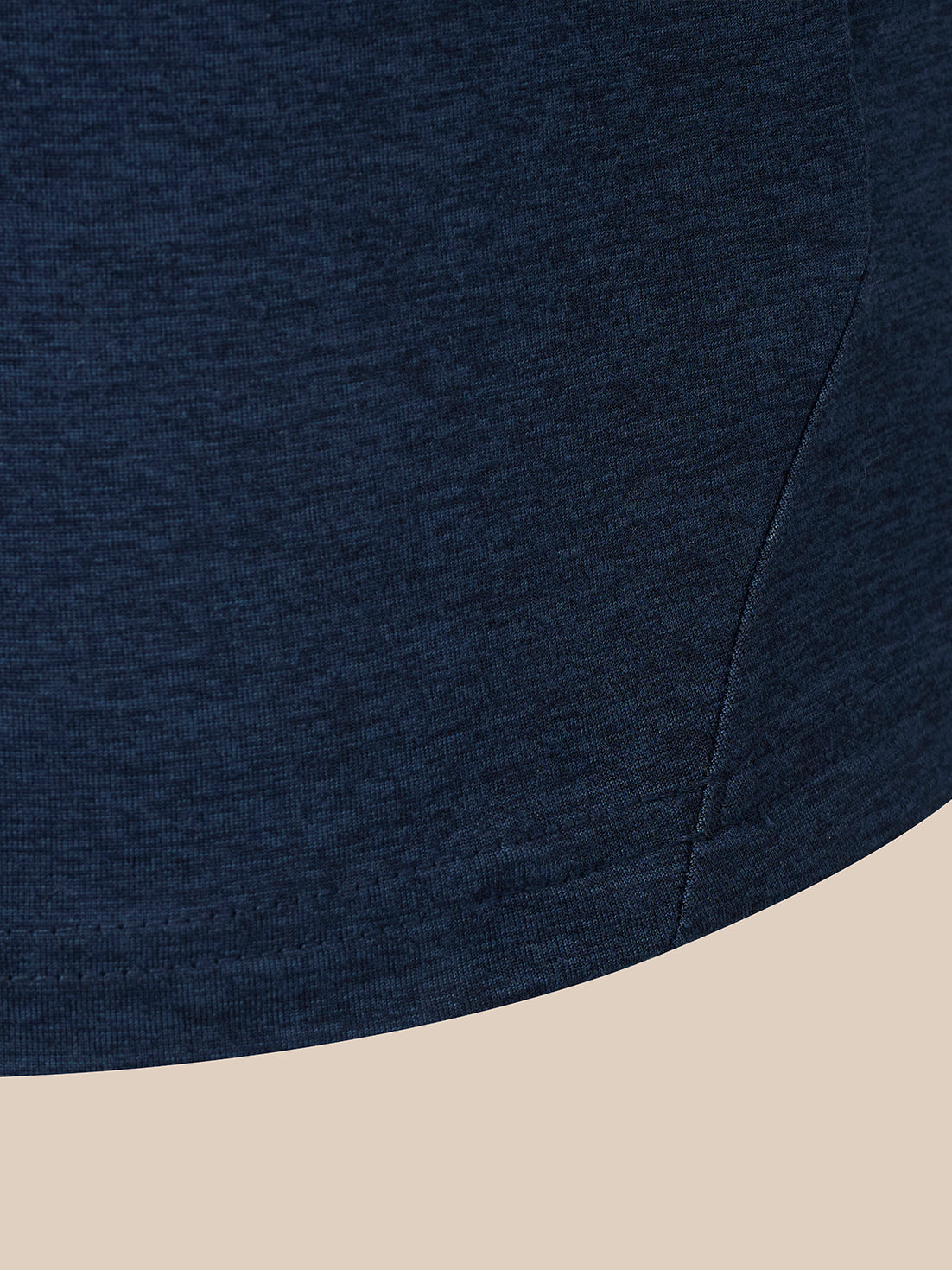 Close-up of a dark navy heathered fabric garment corner with a curved hem, shown against a light beige background.