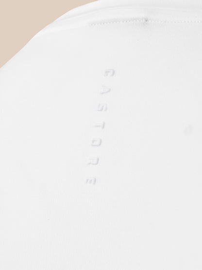 Close-up of a white fabric surface with a vertical embossed 'CASTORE' logo and a small stitched detail near the top, against a light beige background.