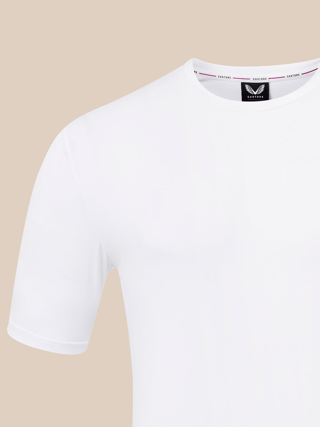 A close-up of a white short-sleeve crewneck t-shirt on a solid beige background, showing the inner neck label with the brand name 'CASTORE'.