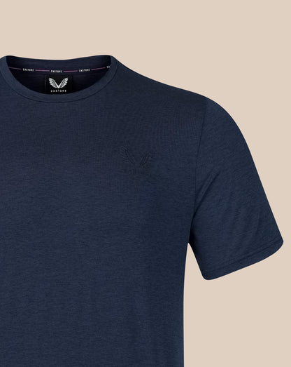 A close-up of a navy blue short-sleeve crewneck t-shirt by Castore, featuring a subtle tonal embroidered logo on the left chest and a visible brand label inside the collar.