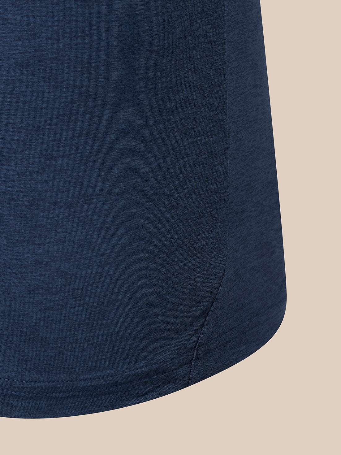 Close-up of a navy blue heathered fabric garment, showing the texture and hem against a solid beige background.