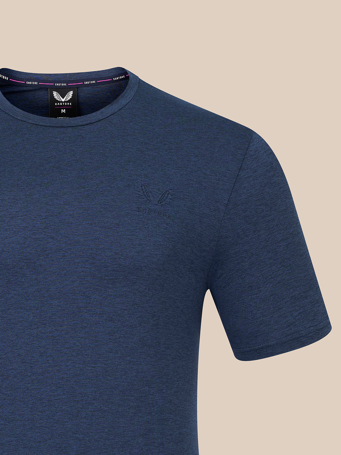 A close-up of a heathered blue short-sleeve crewneck t-shirt by Castore, featuring a subtle tonal embroidered logo on the left chest and a visible neck label.