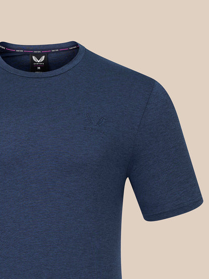 A close-up of a heathered blue short-sleeve crewneck t-shirt by Castore, featuring a subtle tonal embroidered logo on the left chest and a visible neck label.