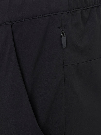 Close-up of a branded zipper pull on a back pocket of black trousers.