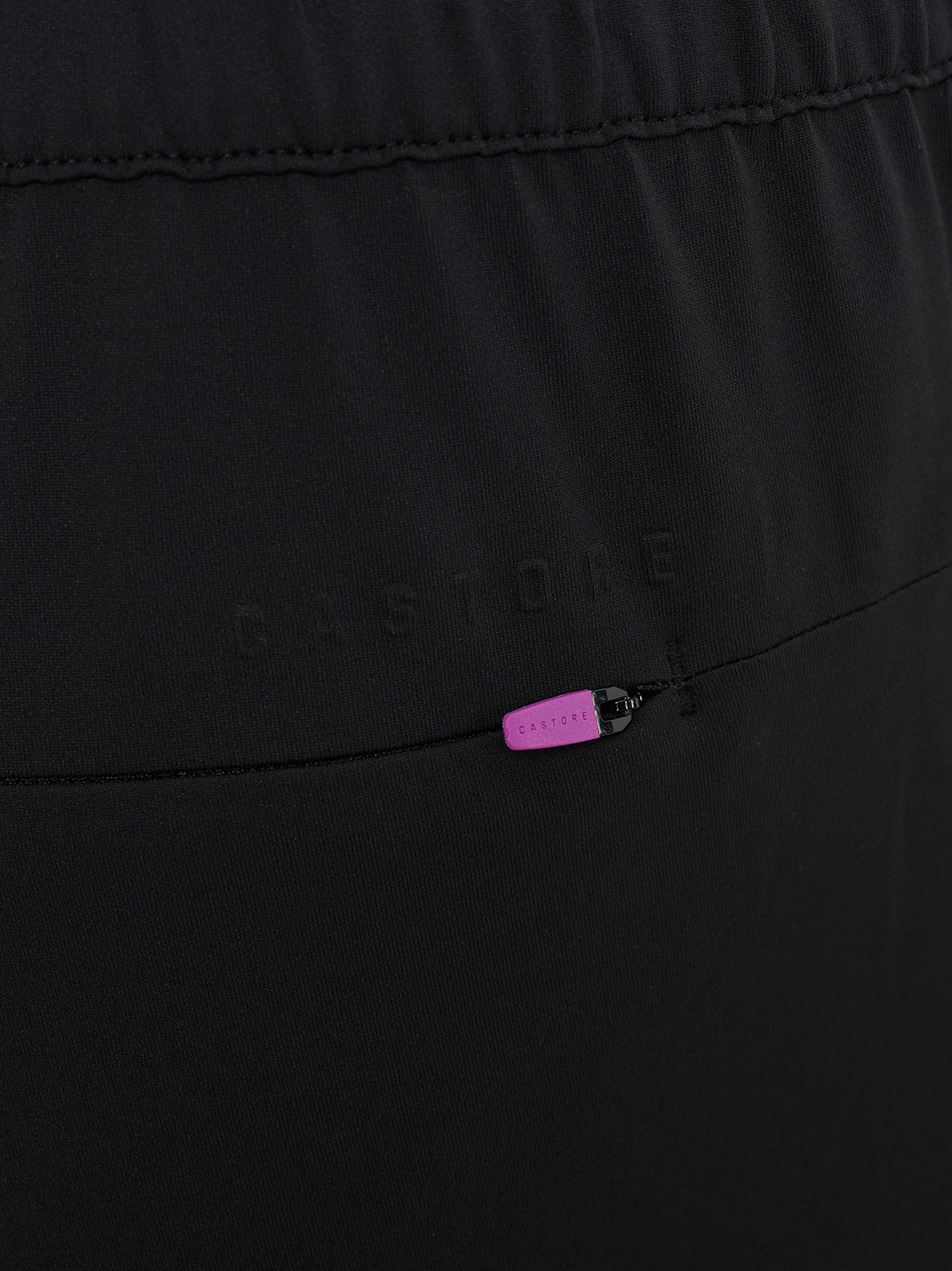 Close up of black elevated lifestyle slim fit trousers with elastic waistband and pink zip pull on back pocket
