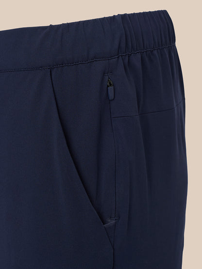 Close up of navy slim fit trousers showing elasticated waistband and side pocket with pink zip pull