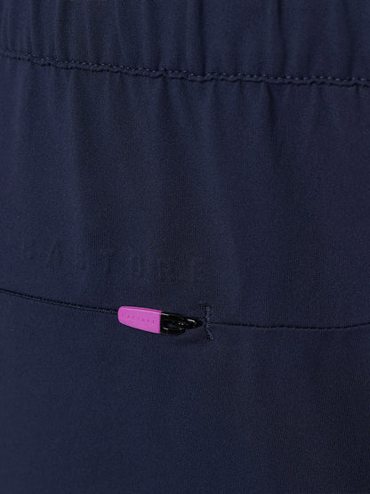 Close up detail of navy trousers featuring a back zip pocket and pink zipper pull